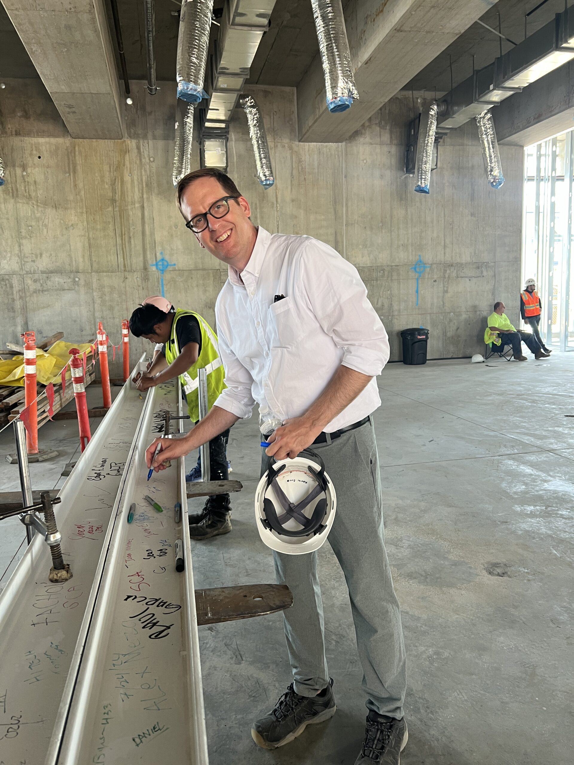 AXIS Principal Architect Kevin Sund signs "the last beam" at the topping-out of the Hilton Arcadia project, an adaptive reuse hotel project designed by Los Angeles architect AXIS Architecture + Design